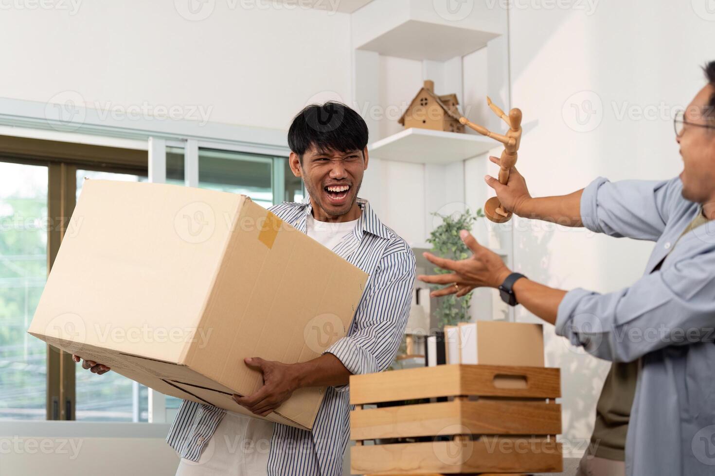 Playful gay couple enjoying unpacking boxes in their shared space photo
