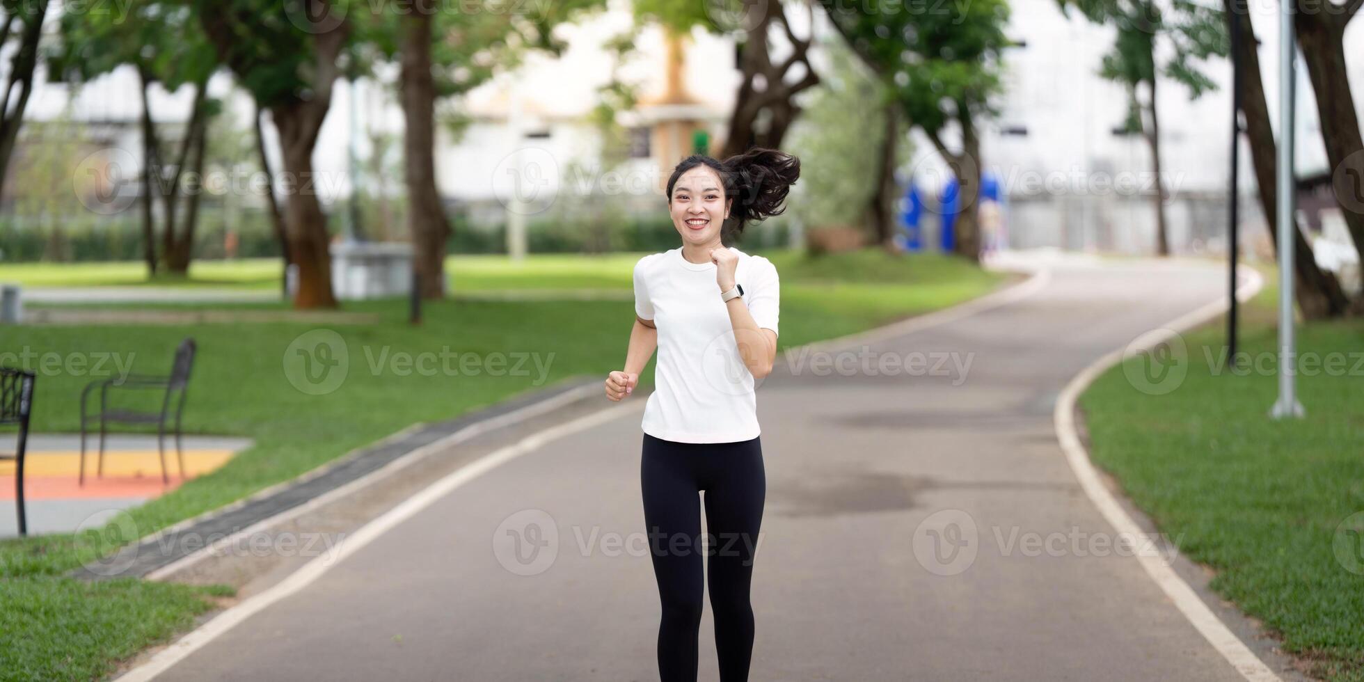 Fitness and Running. Woman jogging happily in a park during her workout. photo