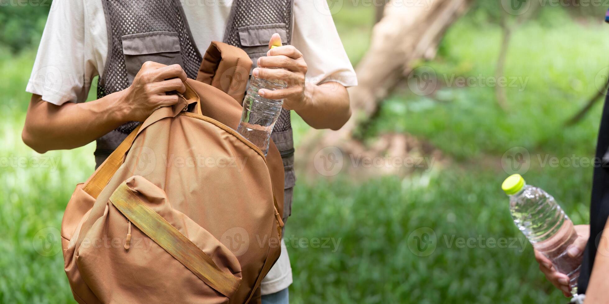 Hiking Essentials. Young Man Packing Water Bottles in Backpack photo