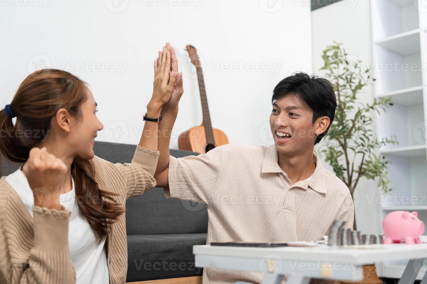 High-Five for Financial Goals. Young Couple Celebrating Savings Together photo