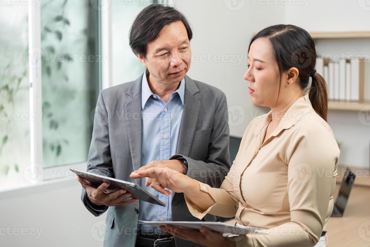 Professional Discussion. Business partners reviewing data on tablets in modern office. photo