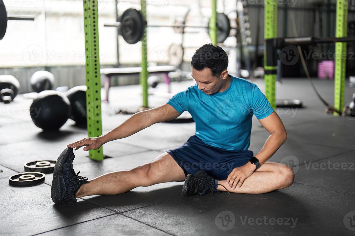 Fitness Stretching Routine. Male athlete performing a hamstring stretch on gym floor. photo