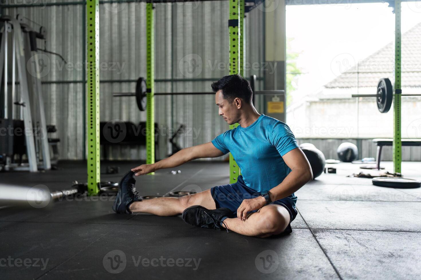 Fitness Stretching Routine. Man performing a seated forward stretch in a gym. photo