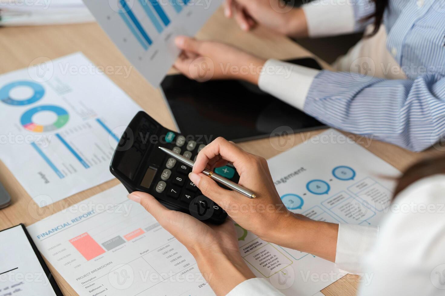Calculating Financial Metrics. Professionals using a calculator for financial analysis and reports. photo