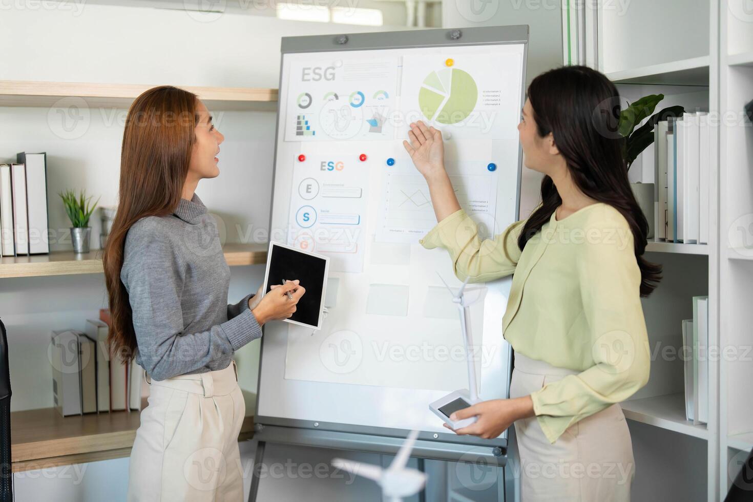 ESG Planning. Women analyzing data for sustainability initiatives in a modern workspace. photo
