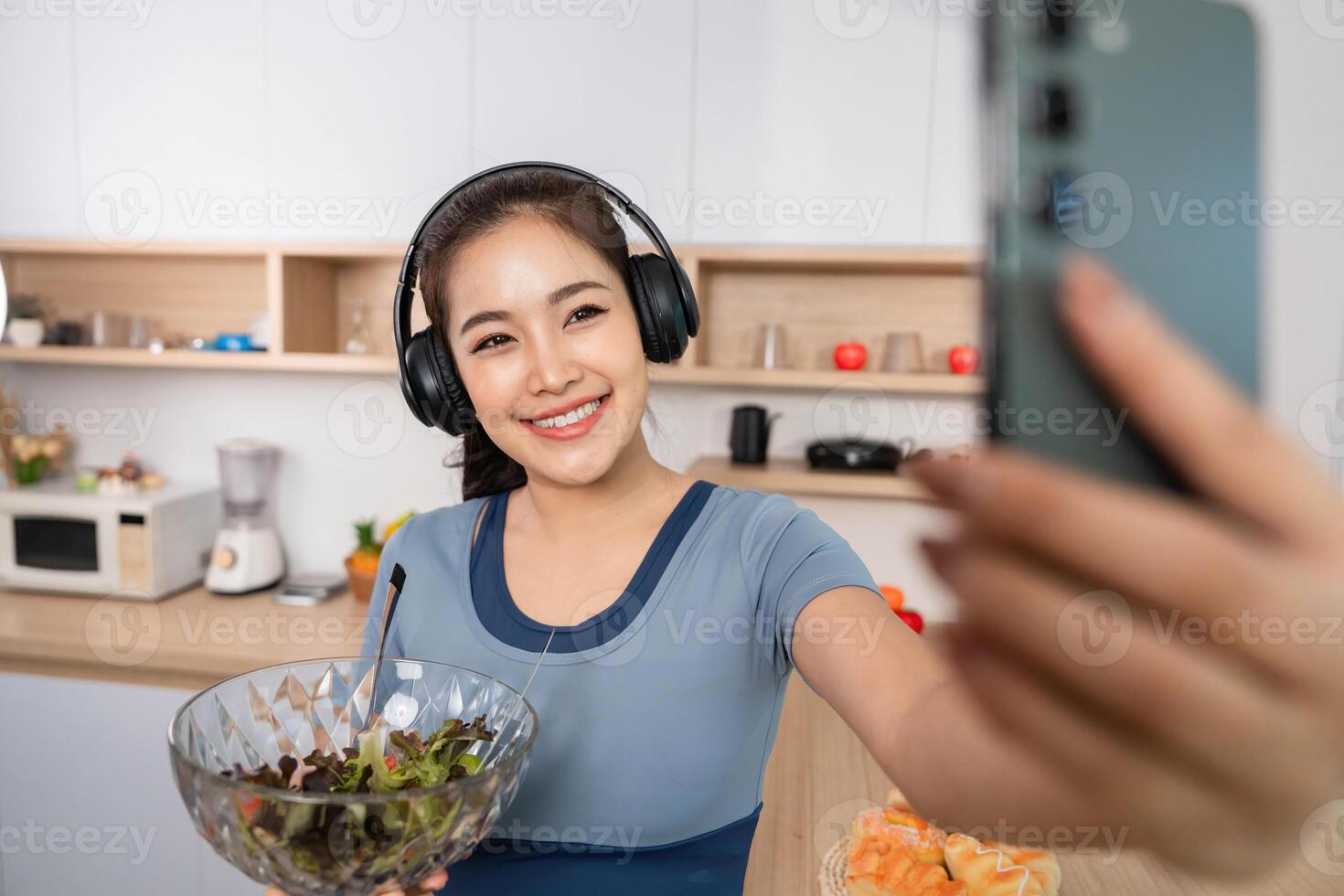 ESG and Healthy Lifestyle. Young woman enjoying a salad while taking a selfie in a modern kitchen. photo