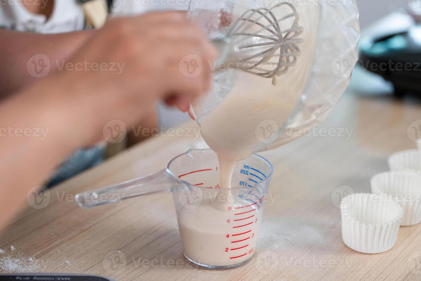 Family Cooking Fun. A child pouring batter into a measuring cup with mom's guidance. photo