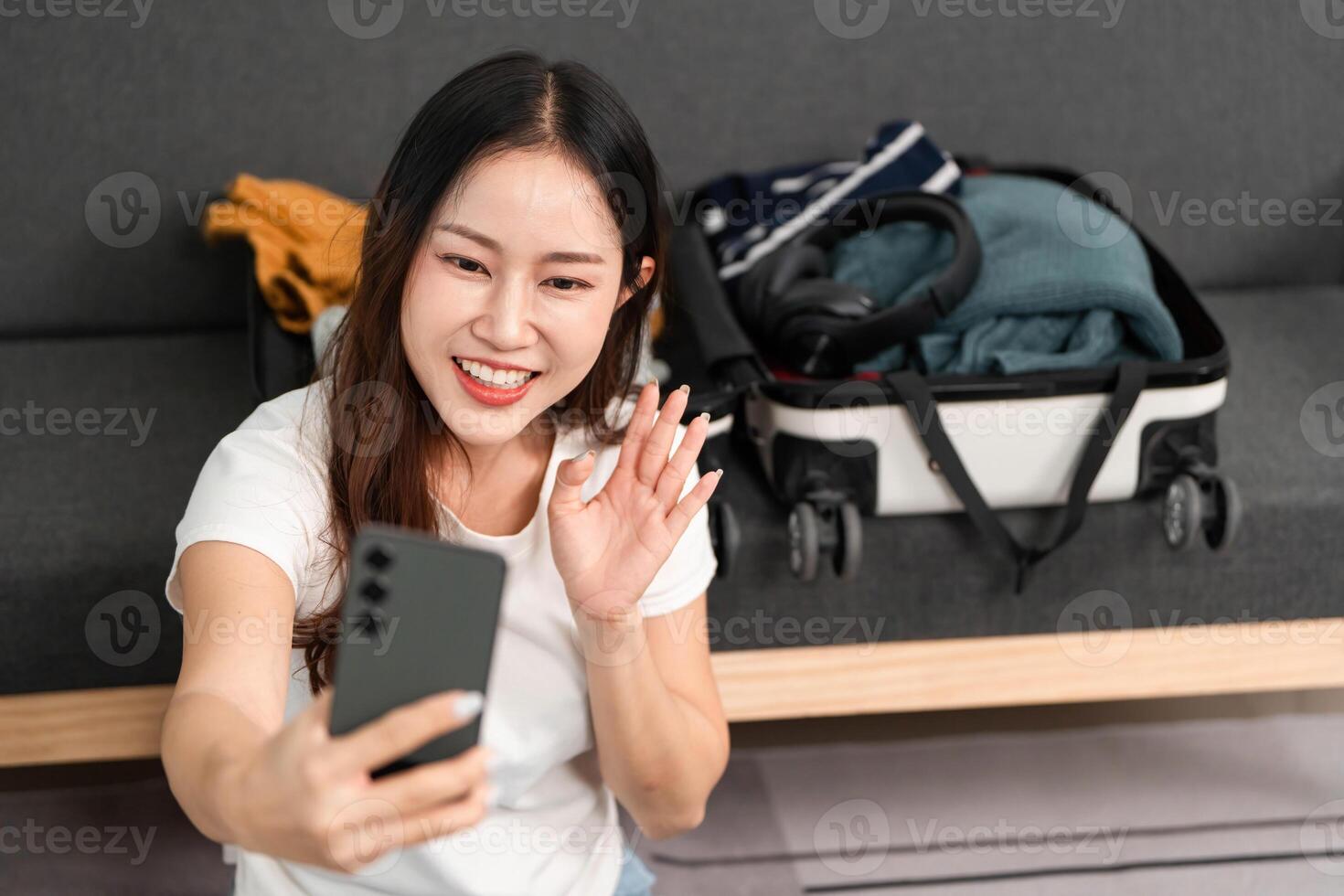 Selfie While Packing. A young woman taking a selfie while preparing her suitcase. photo
