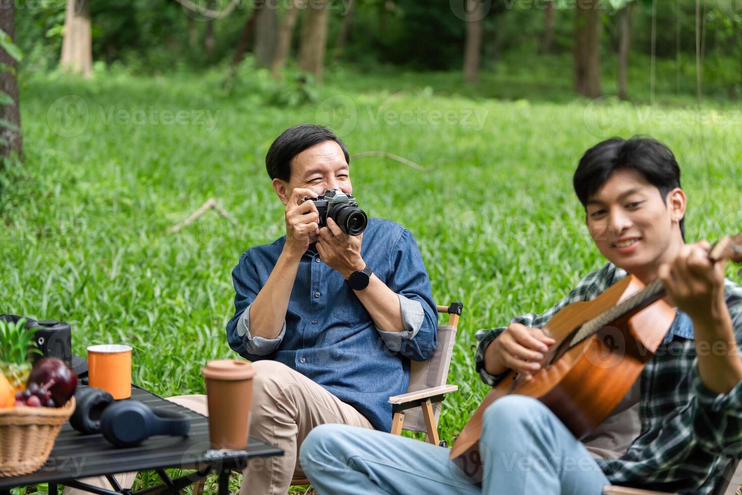 Family fun captured. Father photographing son playing guitar outdoors. photo