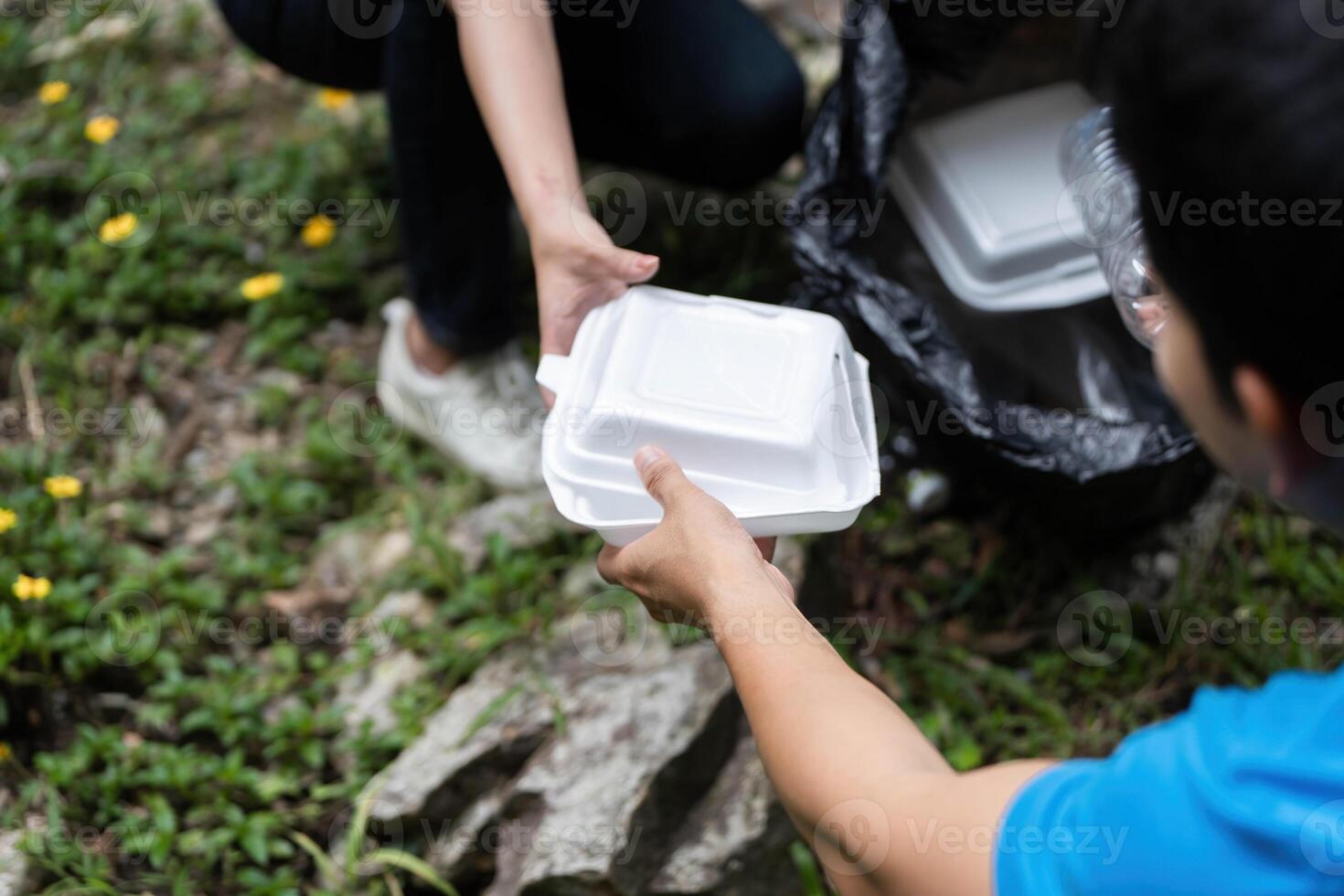 Community Volunteer Action. Two individuals collaborating to remove litter from a natural setting. photo