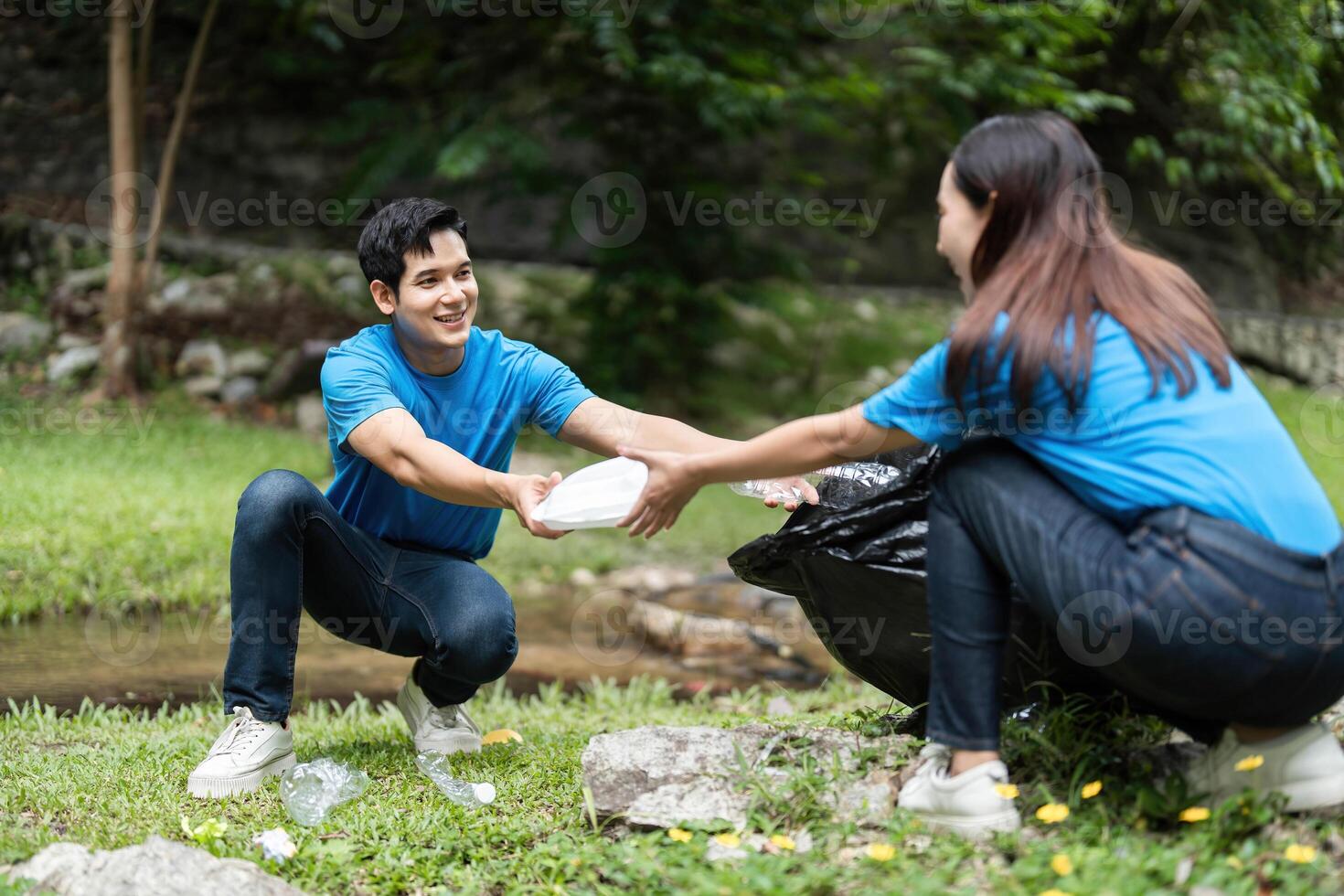Volunteer Team Collecting Waste in Nature. Two individuals engaged in a cleanup effort in a lush setting. photo