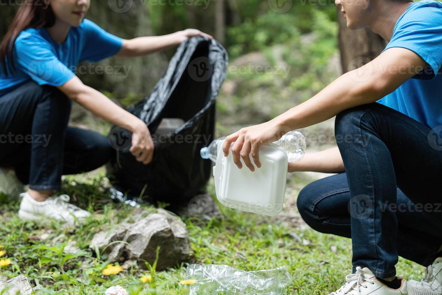 Volunteer Efforts in Nature. Two individuals participating in a community clean-up, collecting plastic waste from a scenic area. photo