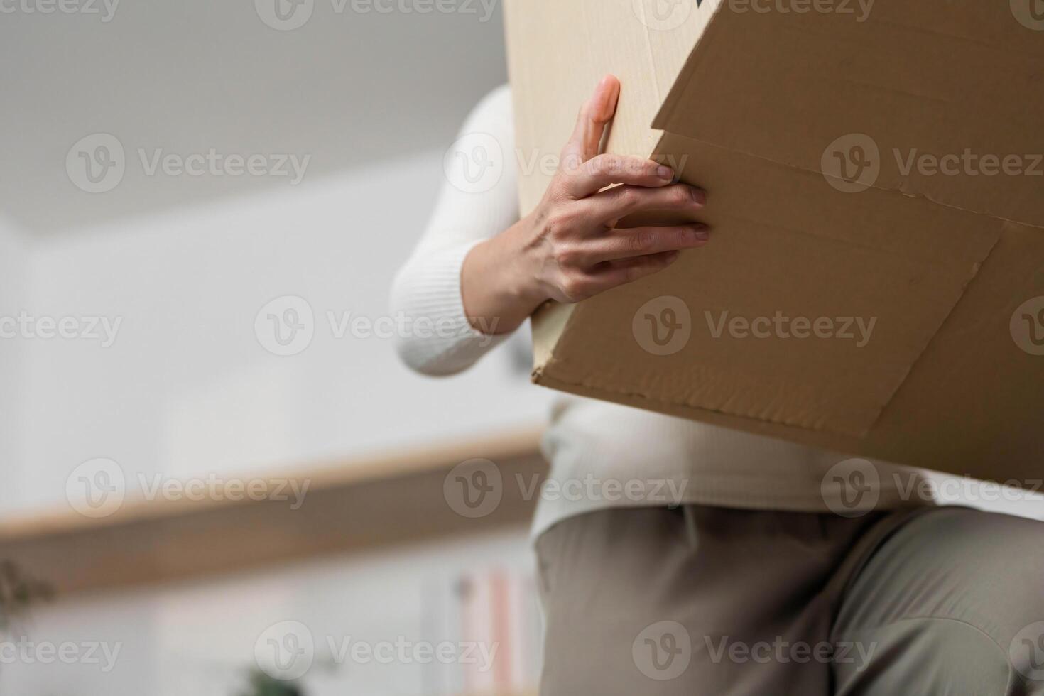 Moving and Lifting. Close-up of woman lifting a cardboard box during relocation. photo