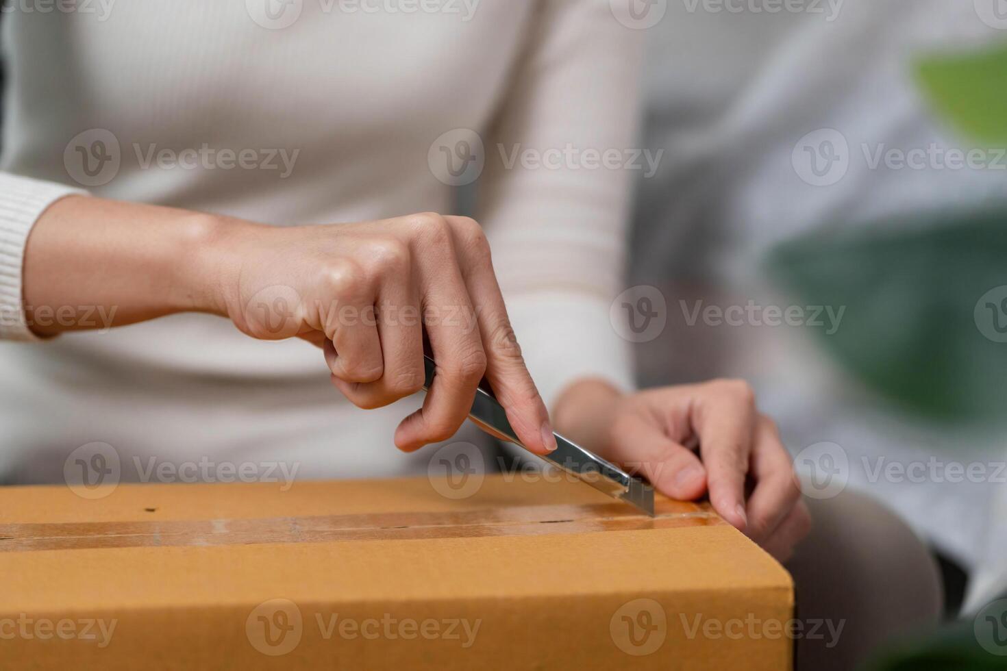 Moving process. Close-up of a woman opening a box with a utility knife. photo