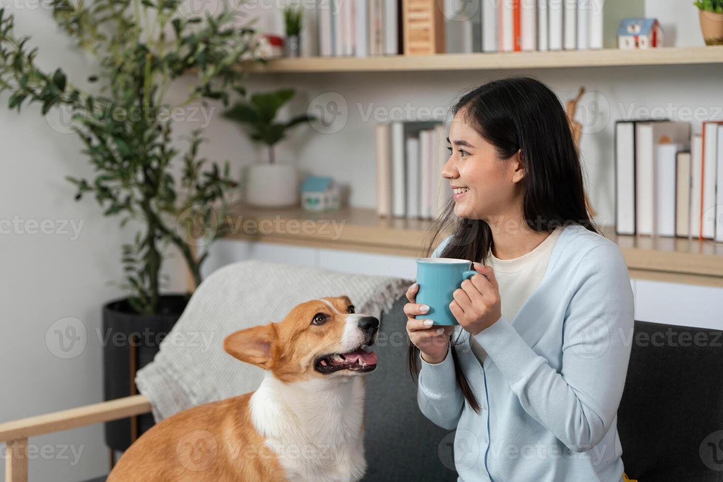 Joyful Coffee Break with Pet. Woman enjoying coffee while her corgi dog looks on. photo
