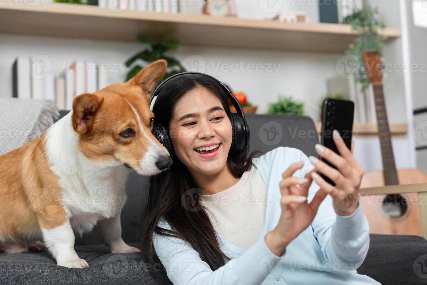 Pet-Friendly Remote Work. Young woman laughing with her dog while using a smartphone at home. photo