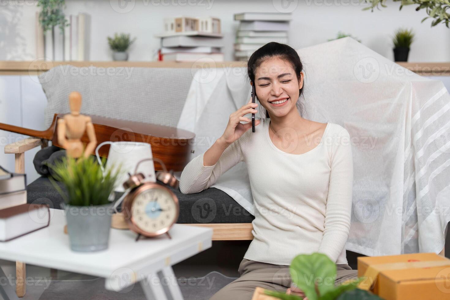 Moving and Connection. A young woman happily chatting on the phone while settling into her new home. photo