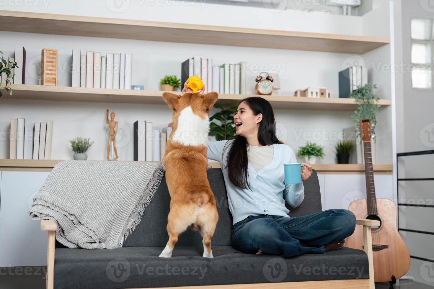 Joyful Moments with Pet. Woman enjoying coffee while playing with her corgi dog at home. photo