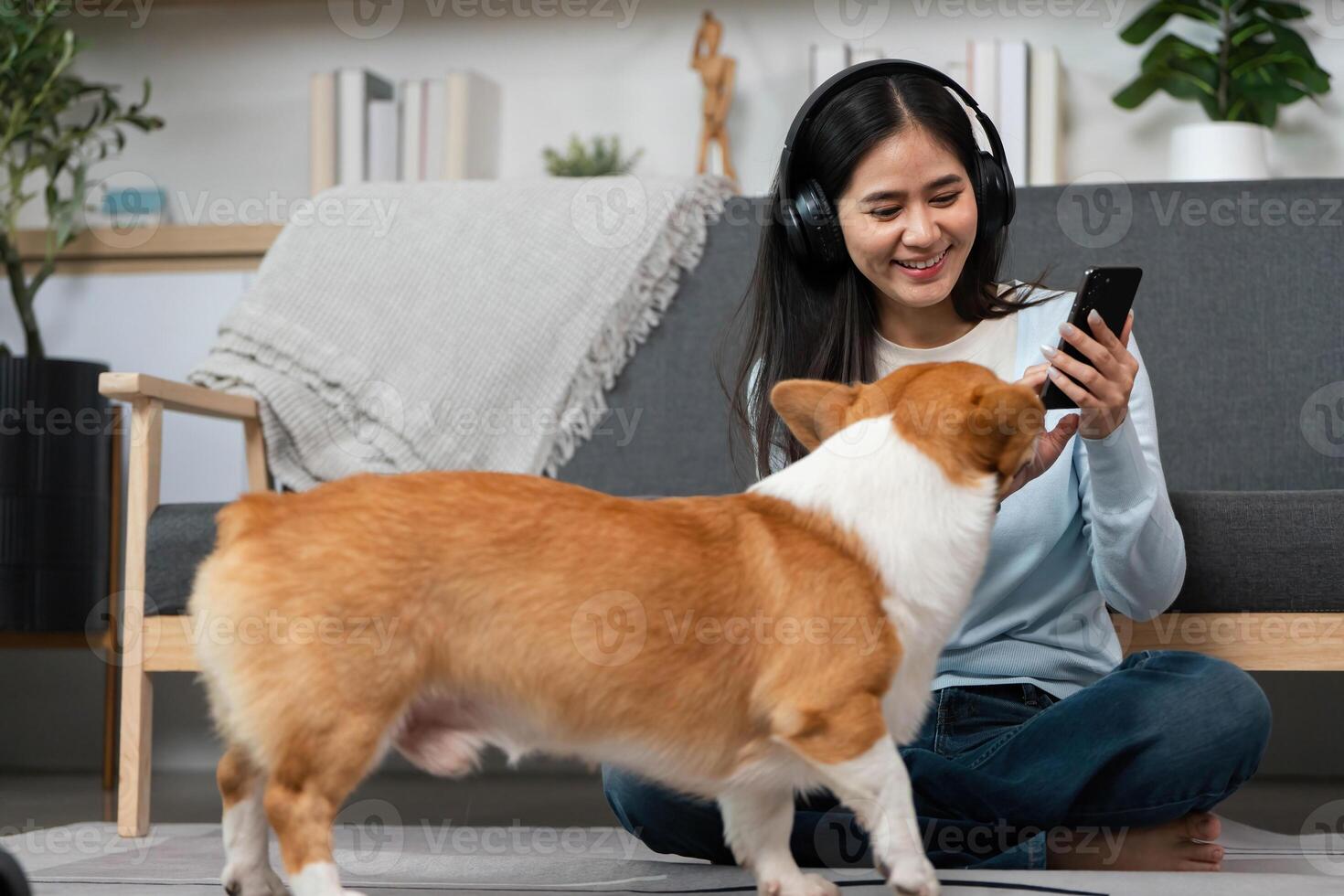 Pet Interaction and Digital Connection. Woman smiling while using smartphone as her dog approaches. photo