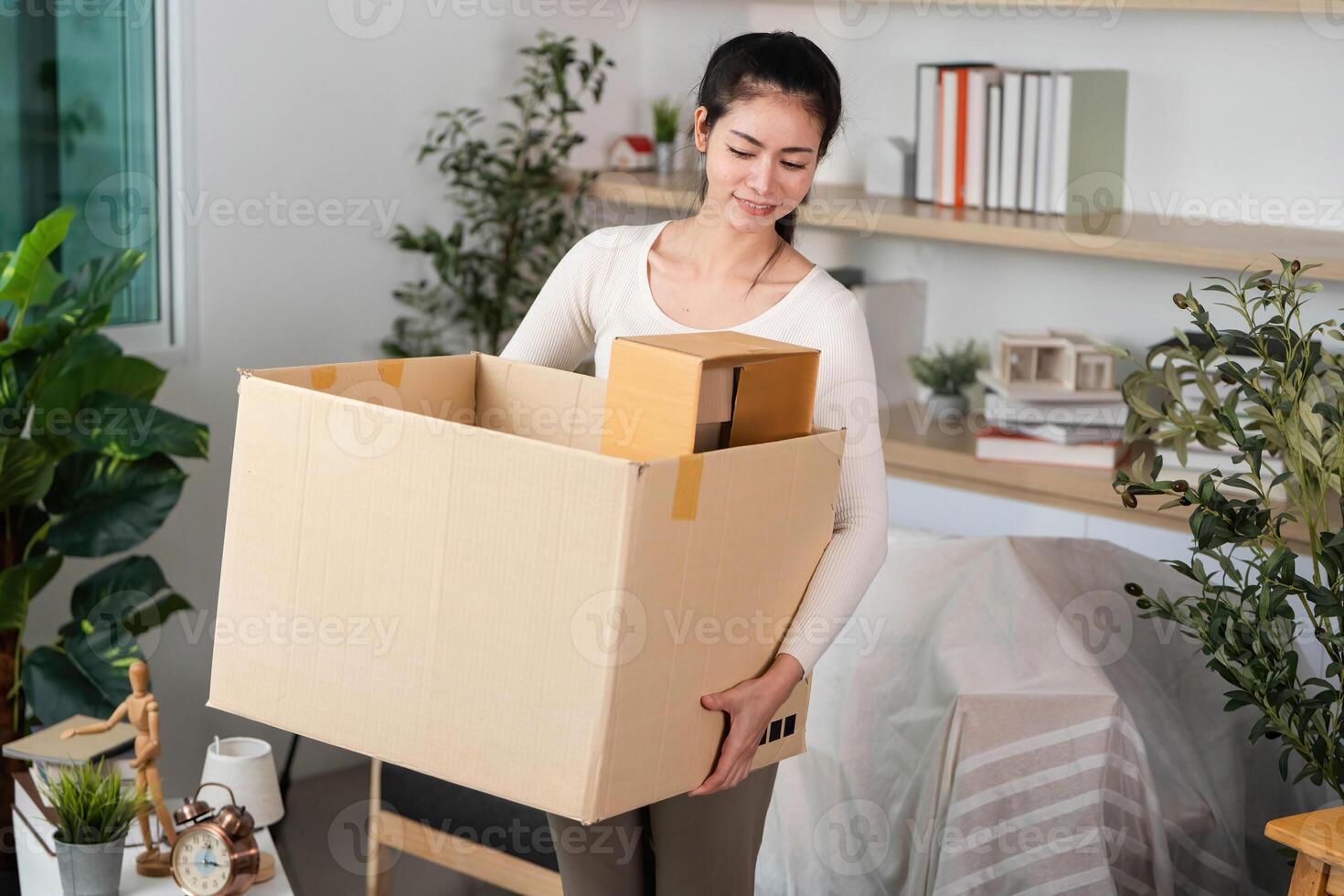 Moving and Packing. Woman carrying a large cardboard box filled with items. photo