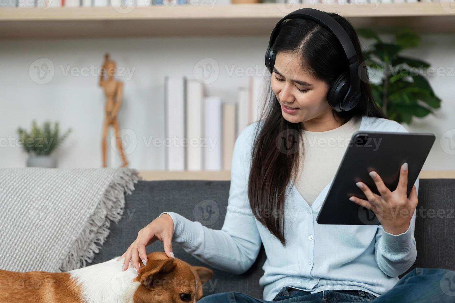 Remote Work and Pet Bonding. Young woman enjoying quality time with her dog while using a tablet at home. photo