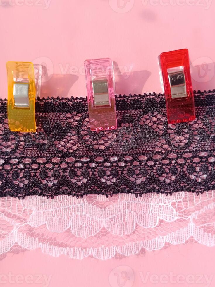 Black lace is secured with sewing and cutting clips of different colors. Hobby sewing and cutting photo
