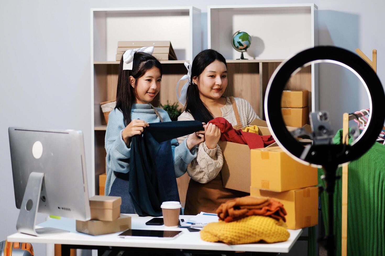 Two women are standing in front of a computer and a camera photo