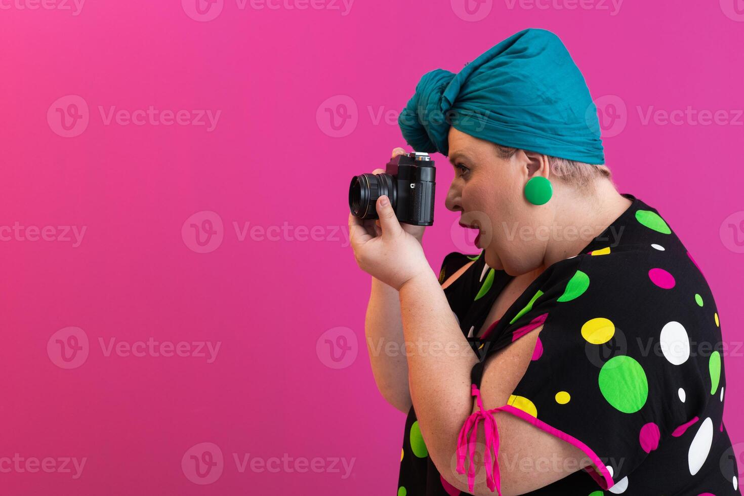 Side view of woman photographer aiming camera in studio photo