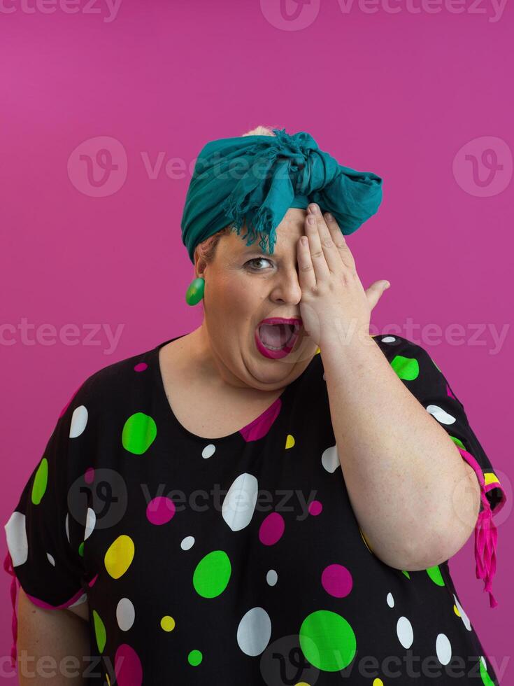 Playful plus-size woman covering eye with hand on colorful background photo