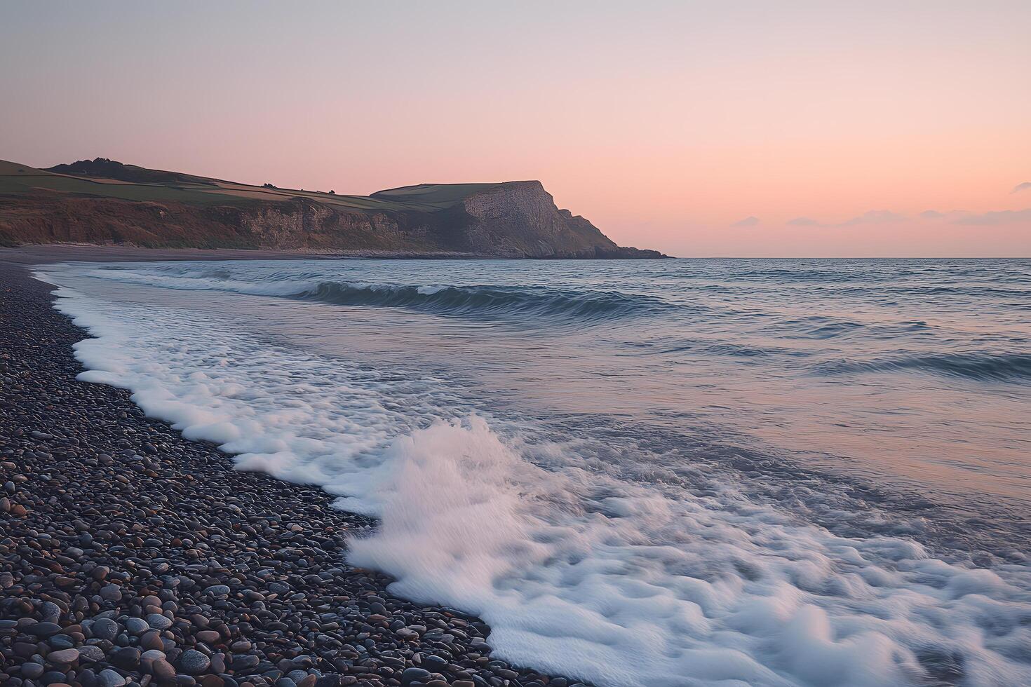 Serene sunset over coastal cliffs waves washing a pebble beach photo