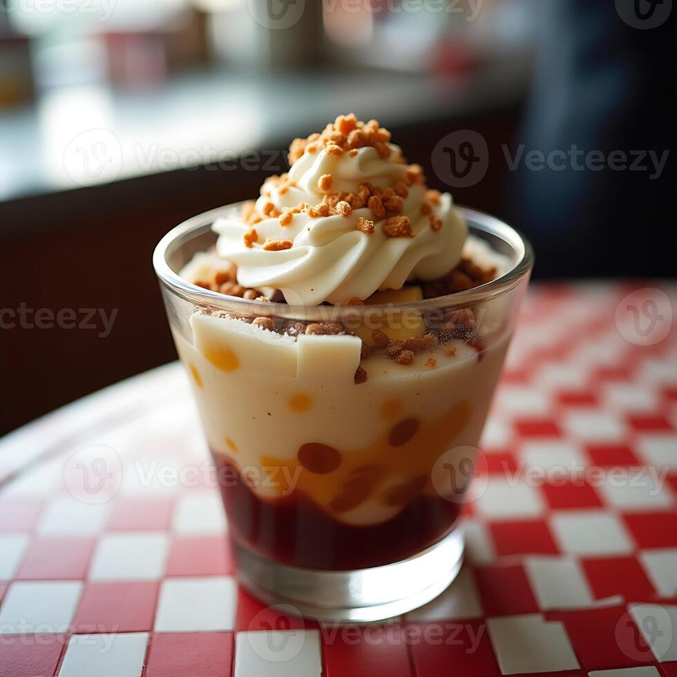 Dessert Parfait in Glass with Whipped Cream and Toppings on Table photo