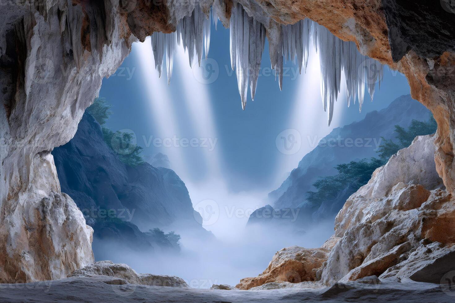 Sunbeams illuminating misty mountains from inside a cave with stalactites photo