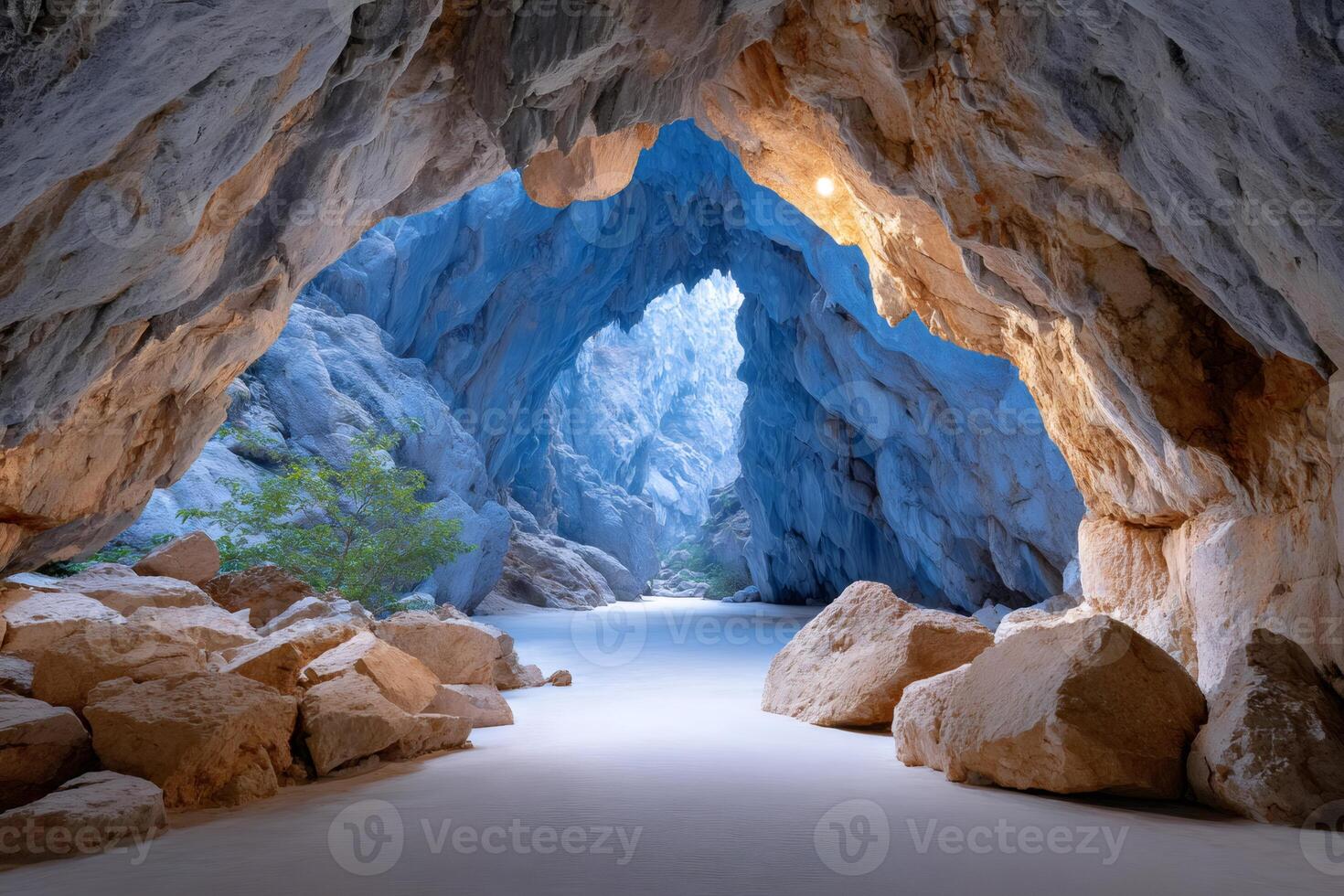 Sunlight entering blue cave with white sand and rocks photo