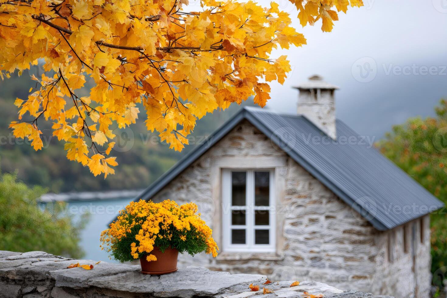 Yellow flowers and autumn leaves decorating a stone house by the lake photo