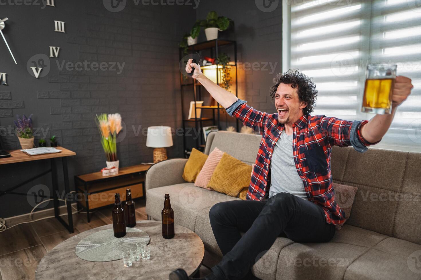 Excited man celebrating watching sports on tv with beer photo