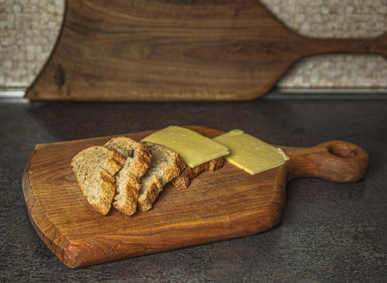 A casual, cozy setup of bread, cheese, and a cutting board in a warm-lit kitchen. The photo suggests a slow and thoughtful approach to everyday food. Great for storytelling in cooking or lifestyle