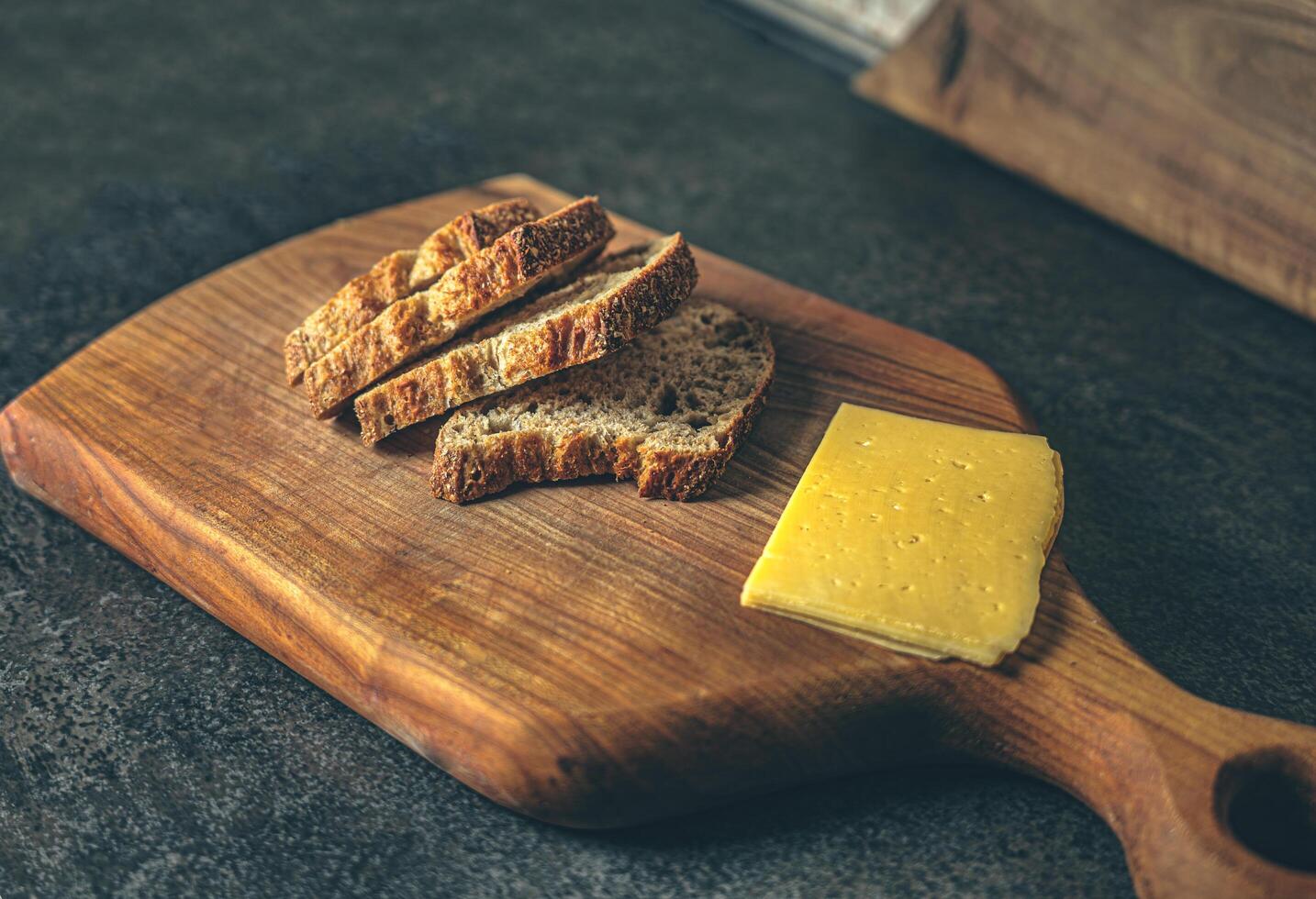 A step-by-step view of sandwich preparation with cheese and bread on a kitchen table. Natural textures and light create a warm, inviting image. Ideal for food blogs, recipe sites, or cooking photo