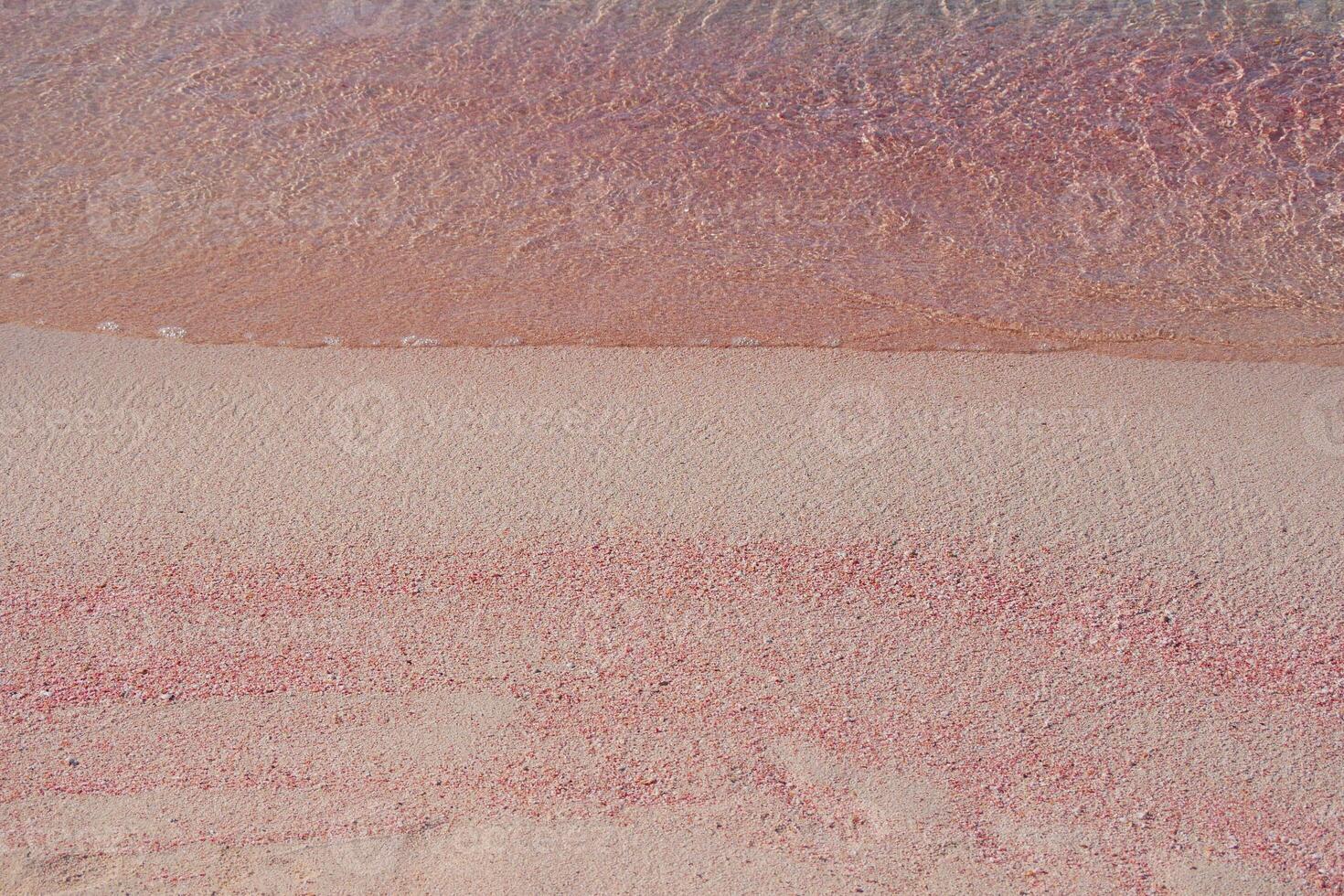 Pink sand and sea wave. Beach with pink sand in Elafonisi, Krit, Greece. Design background wallpaper with copy space. Sand texture pattern photo