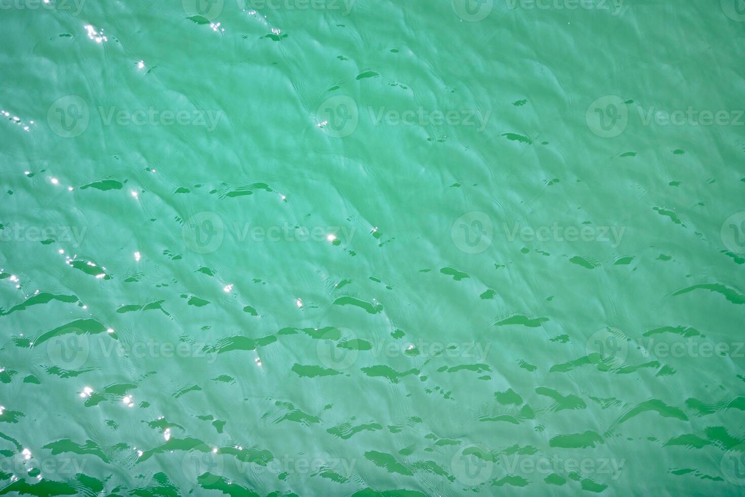 Water surface topview. Sun glare on water. Background abstracted wallpaper texture photo