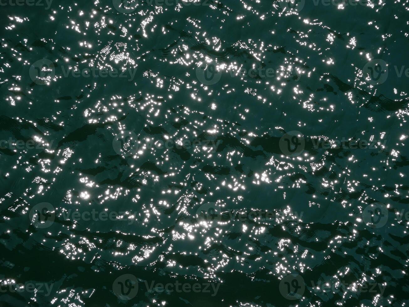 Water surface high contrast topview. Sun glare on water. Background abstracted wallpaper texture photo