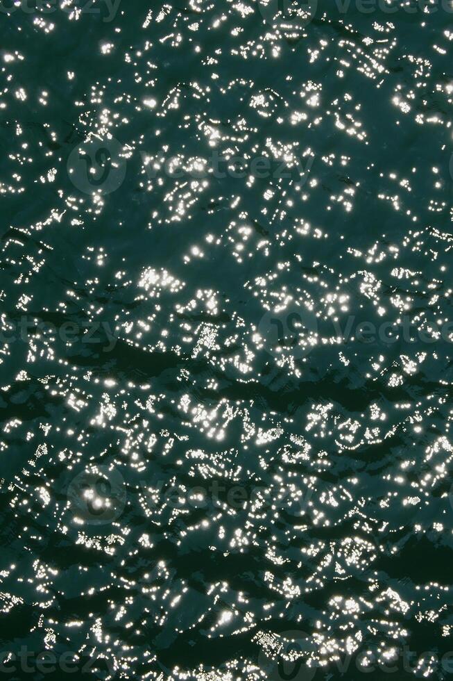 Water surface highcontrast top view. Sun glare on water. Background abstracted wallpaper texture photo