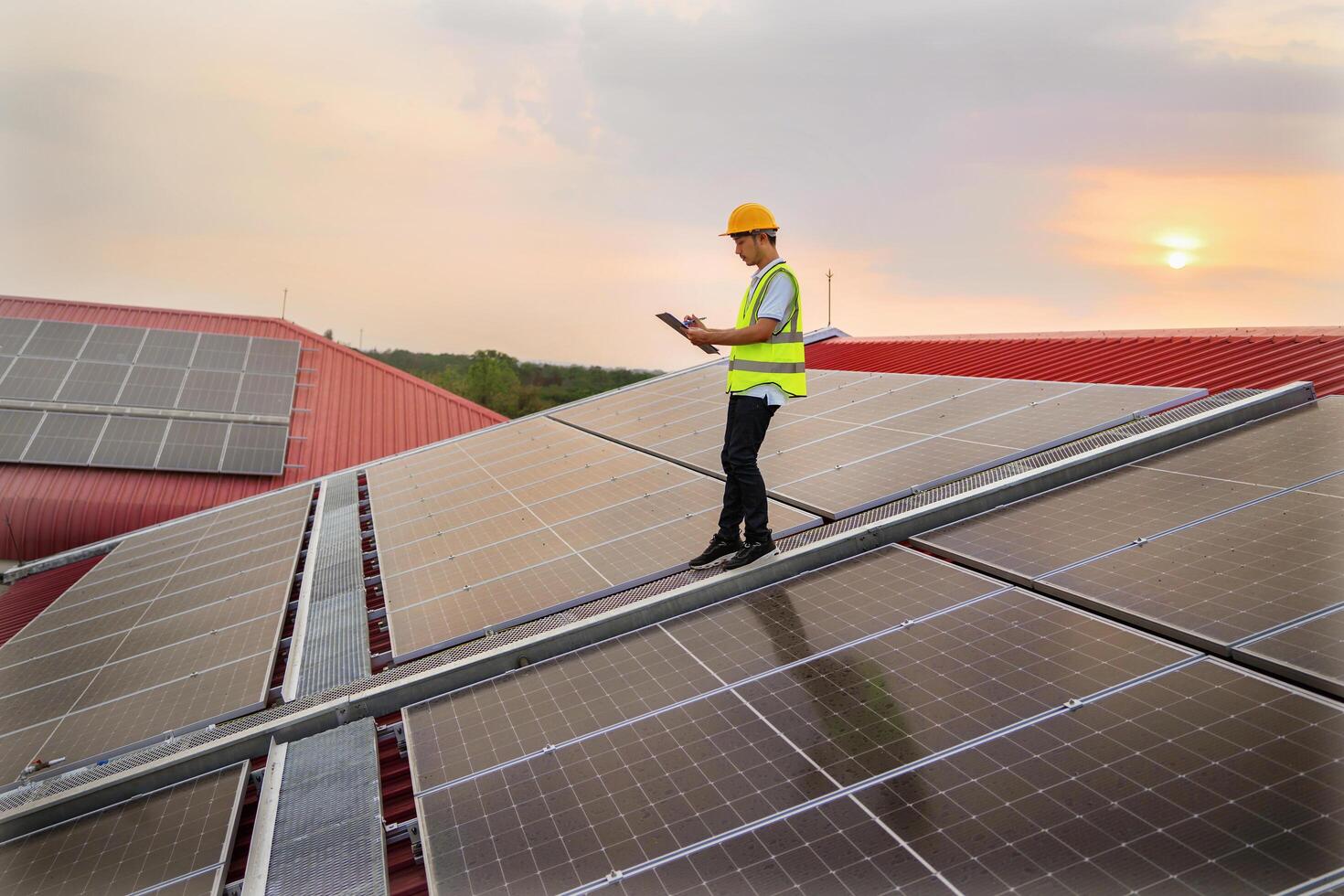 man in yellow vest walking on a roof with solar panels photo