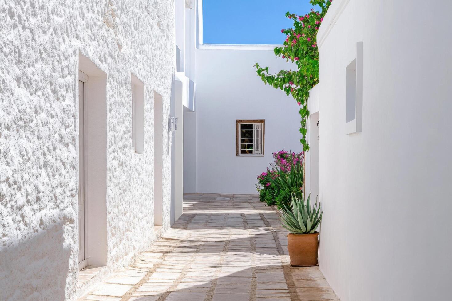 Sunlit Mediterranean Architecture A Serene Whitewashed Alleyway. Discover the charm of sun drenched stone pathways, vibrant flower photo