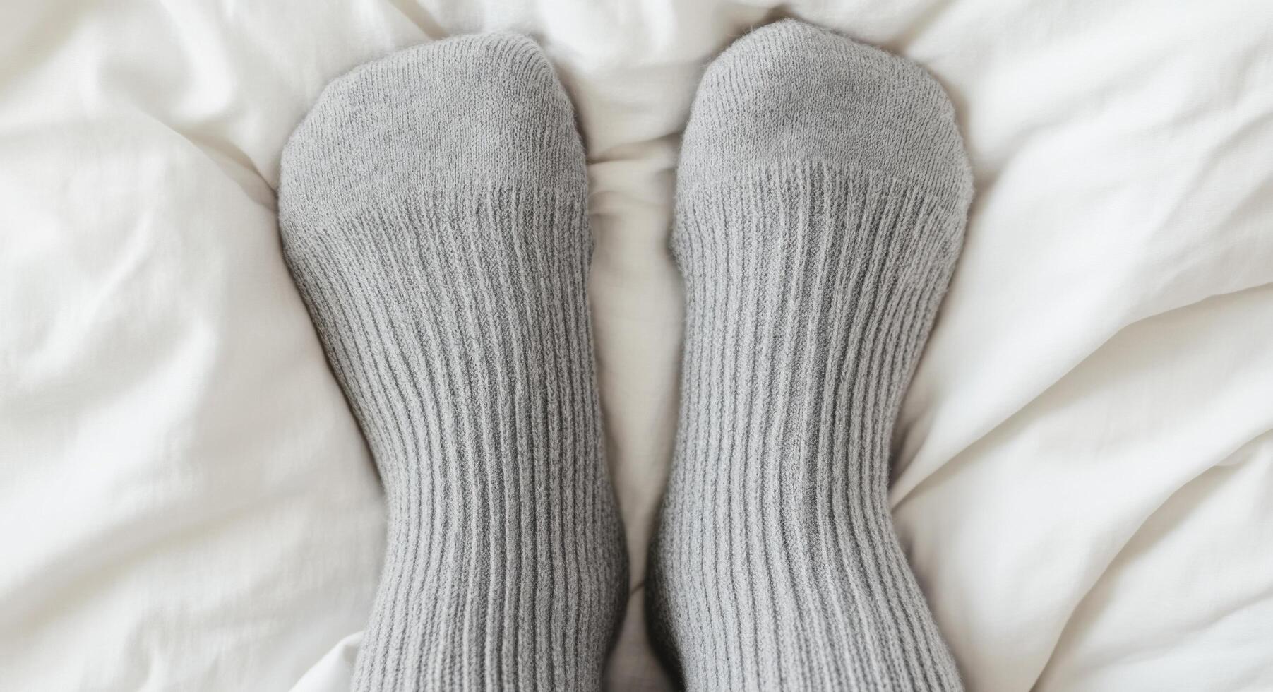 Cozy Grey Socks on a White Bed A Symbol of Relaxation and Comfort at Home. Find peace and tranquility in the simple pleasures of l photo