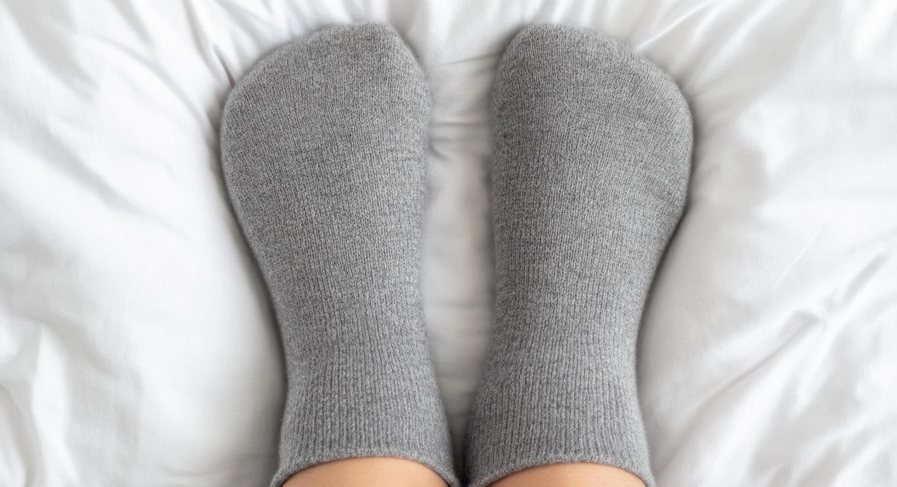 Cozy Grey Socks on a White Bed A Symbol of Comfort and Relaxation at Home. Perfect for a peaceful morning, this image evokes feeli photo