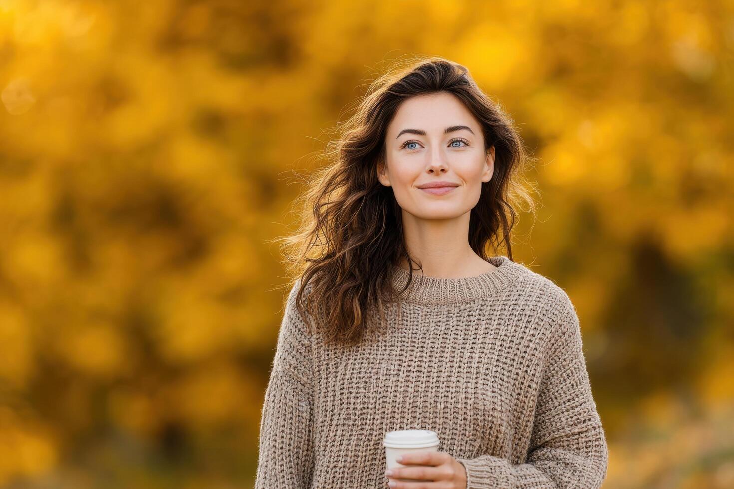 Smiling woman enjoying a coffee in an autumn park. A beautiful portrait of a happy person surrounded by golden leaves and warm su photo