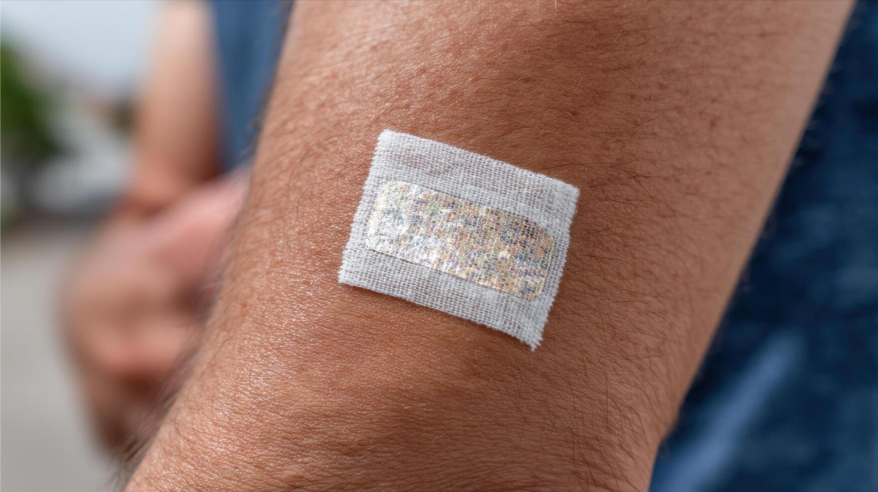 of a medical sensor patch on human skin. This image depicts a small, square, wearable technology device used for health monitorin photo