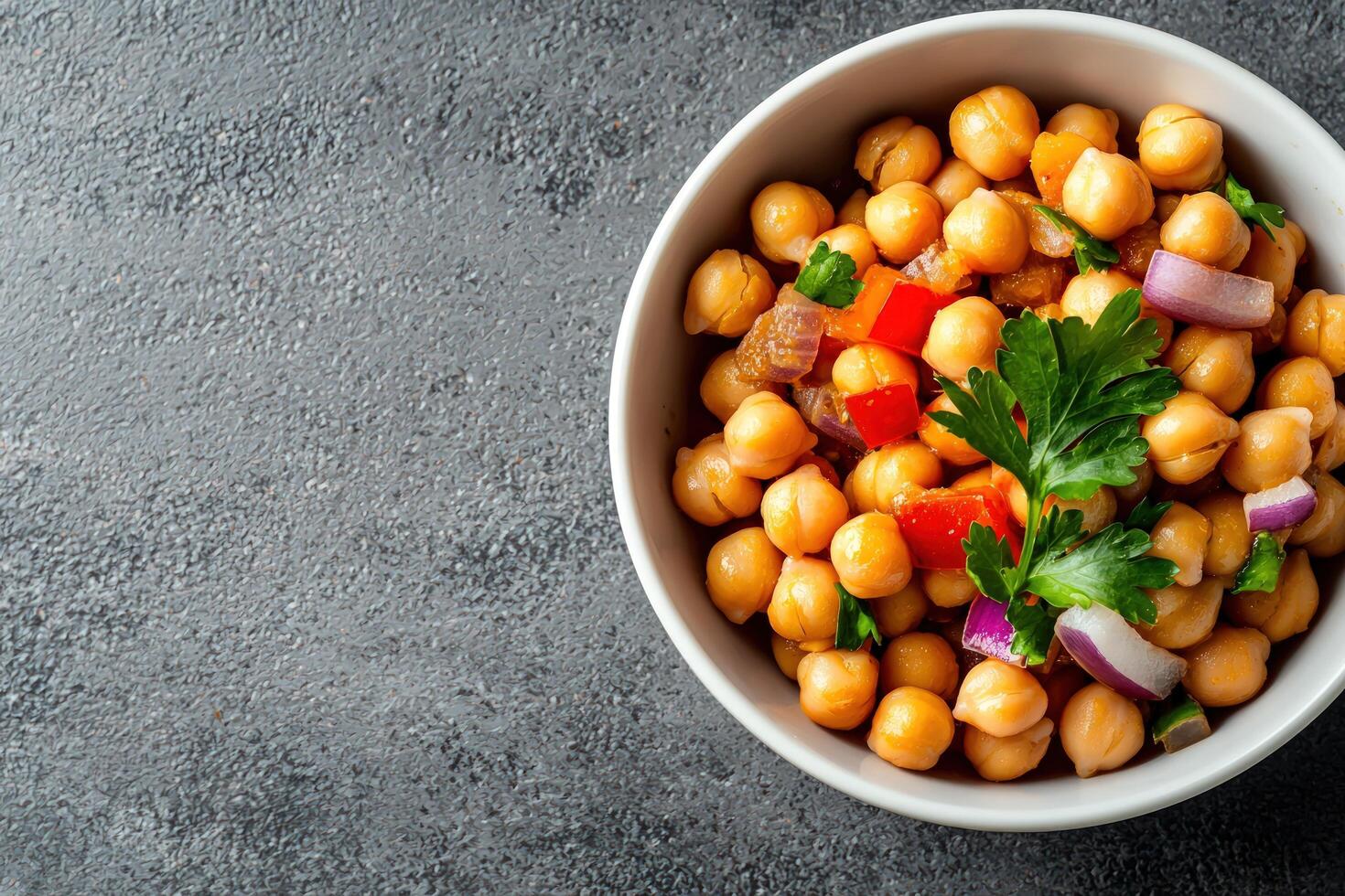 Chickpea salad with herbs and red onion in bowl on dark background photo
