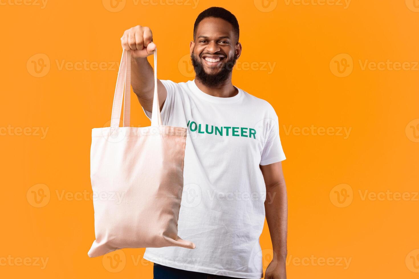 Stop Using Plastic. African Volunteer Man Showing White Eco Bag To Camera Posing Standing On Yellow Studio Background. Consumerism And Ecology, Plastic-Free Lifestyle photo