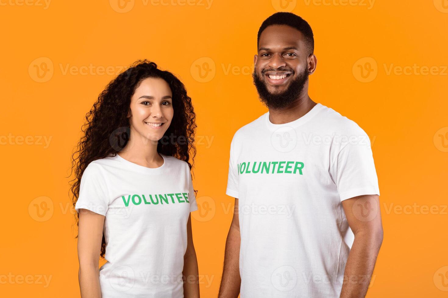 Volunteering Work. Female And Male Multiracial Volunteers Posing Smiling To Camera Wearing White Uniform T-Shirts Standing On Yellow Studio Background. Contribution, Community, Activists Portrait photo